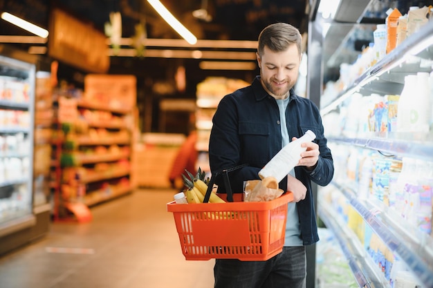 Portrait of smiling man walking with his trolley on aisle at supermarket