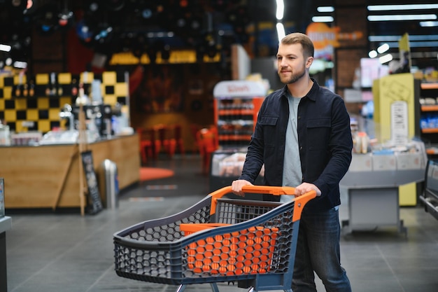 Portrait of smiling man walking with his trolley on aisle at supermarket