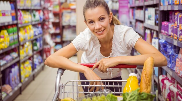 Portrait of smiling man walking with his trolley on aisle 