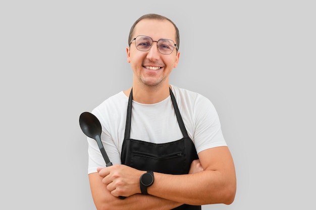 Portrait of smiling man wearing apron looking at camera on gray background