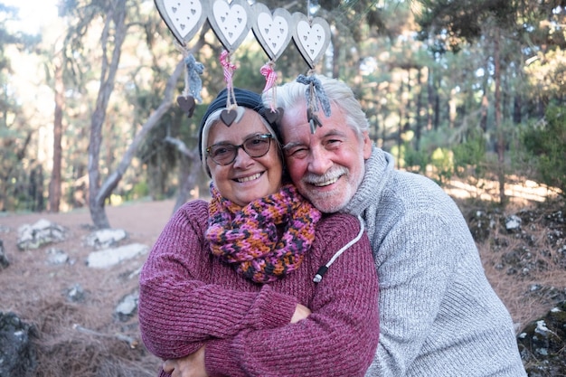 Foto ritratto di un uomo e una donna sorridenti che si abbracciano contro gli alberi nella foresta