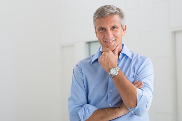 Portrait Of Smiling Mature Businessman With Hand On Chin