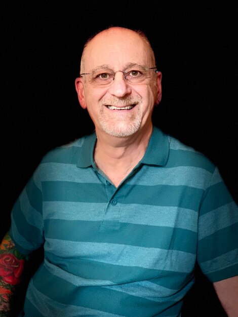 Portrait of smiling mature man against black background