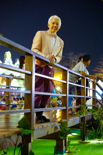 Portrait of smiling mature man standing footbridge over stream at night