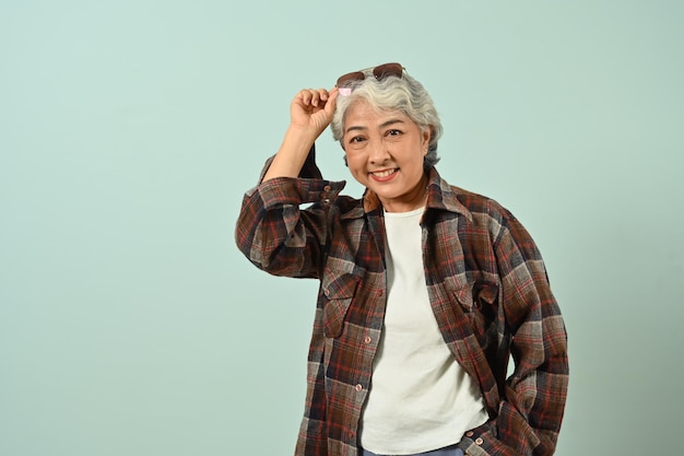 Portrait of smiling mature woman wearing plaid shirt isolated on bright blue color background