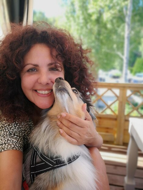 Photo portrait of smiling mid adult woman with dog at home