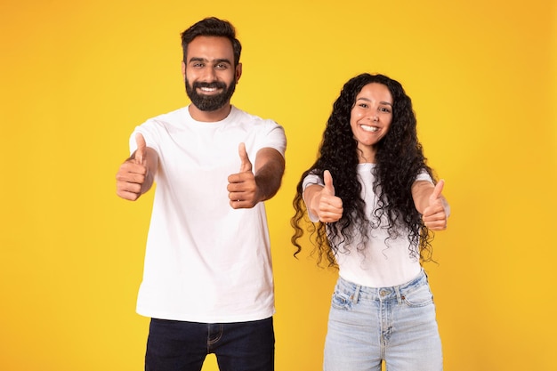 Portrait of smiling middle eastern couple showing thumbs up studio