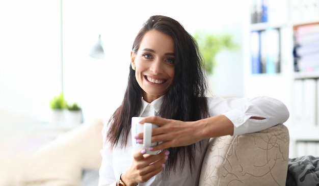 Ritratto di donna d'affari dipendente di successo mentalità sorridente in camicia bianca con tazza