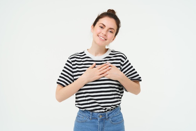 Foto ritratto di una donna moderna sorridente che tiene le mani sul cuore e dice grazie esprimendo i suoi sentimenti caldi