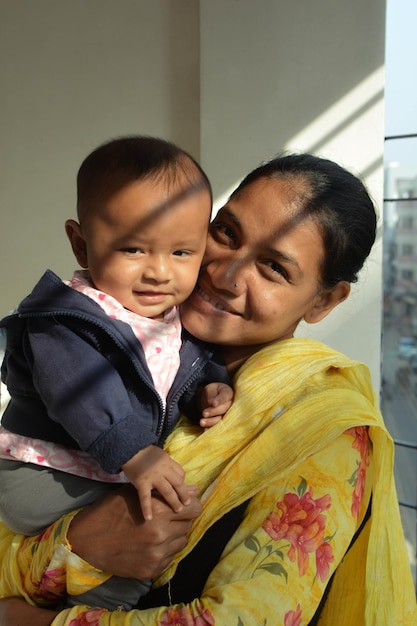 Photo portrait of smiling mother carrying cute son at home