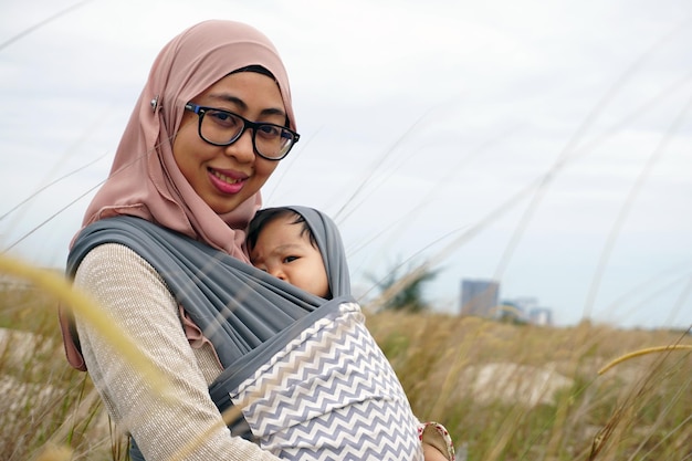 Photo portrait of smiling mother carrying daughter on field