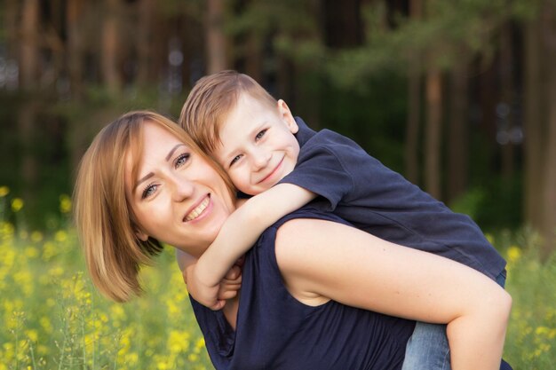 Foto ritratto di una madre sorridente che porta il figlio sulla schiena