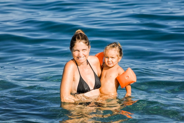 Photo portrait of smiling mother and daughter in sea