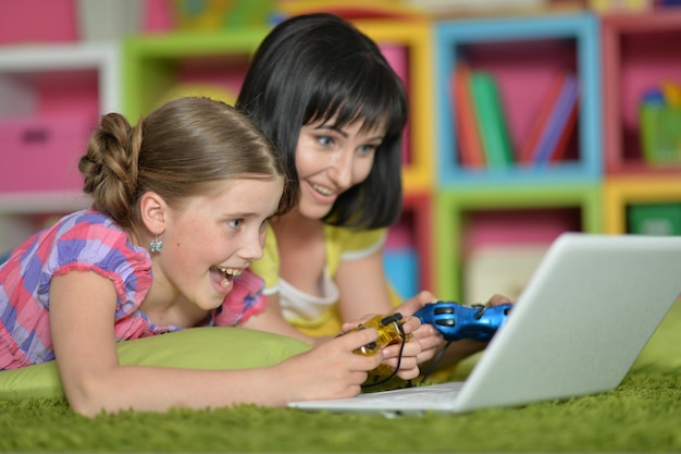 Portrait of smiling mother and daughter using laptop playing video game