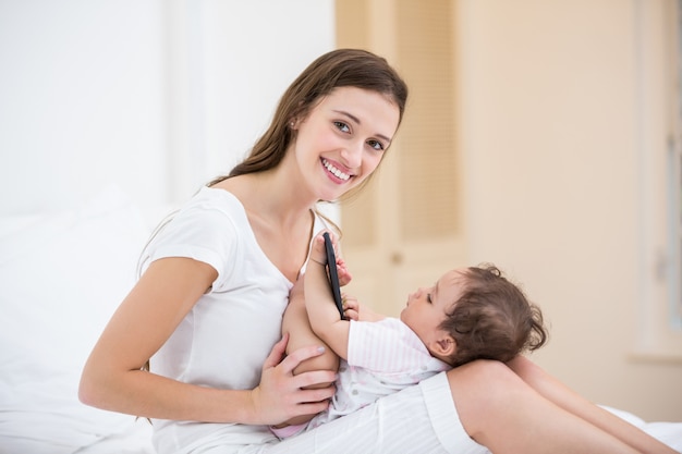 Portrait of smiling mother with baby holding mobile phone 