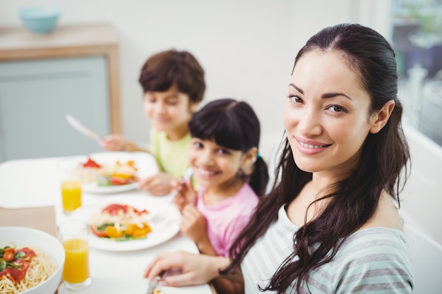 Ritratto della madre sorridente con i bambini al tavolo da pranzo