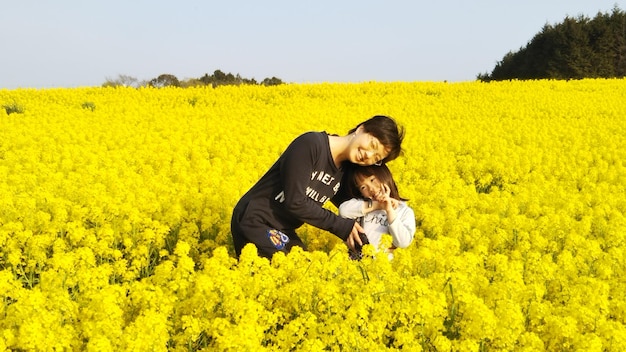 Portrait of smiling mother with daughter standing amidst yellow flowers