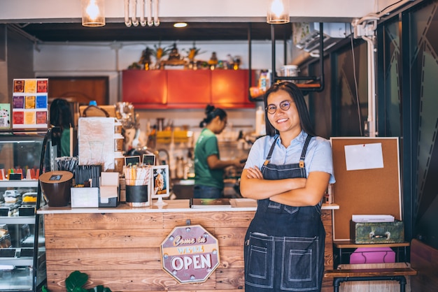 Portrait of smiling owner standing at coffee shop, small family business. Portrait of smiling owner standing at front counter bar