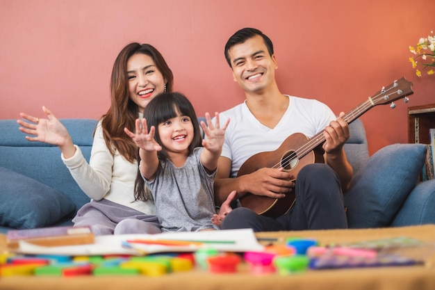 portrait of smiling parents sitting with daughter on sofa in living room at home