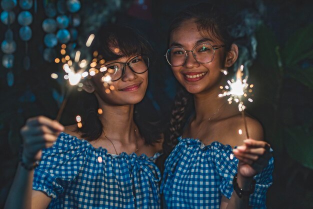 Photo portrait of smiling people holding sparklers at night