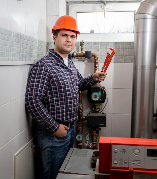 Portrait of smiling plumber posing with pliers at boiler room