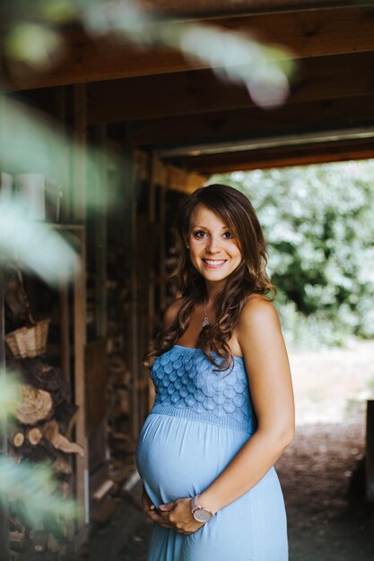 Photo portrait of smiling pregnant woman wearing blue dress standing in park