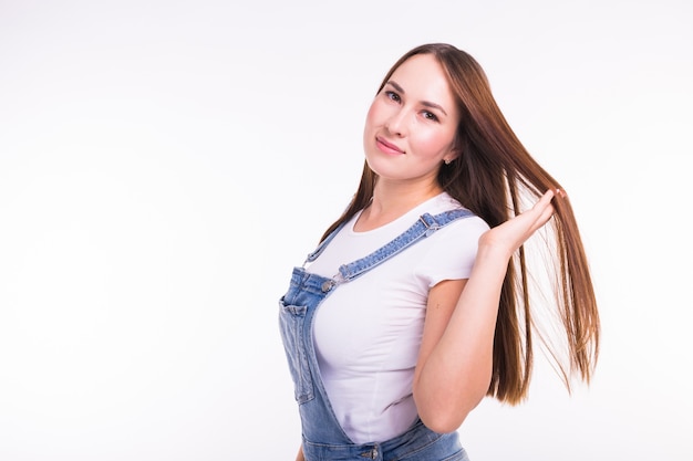 Portrait of a smiling pretty woman in denim overall isolated on white wall with copy space.