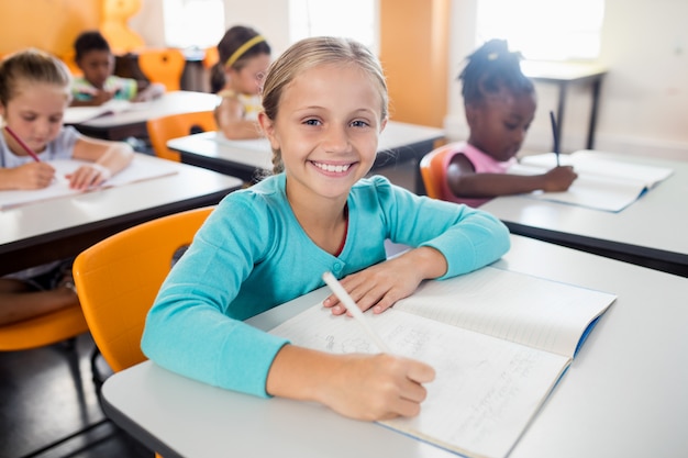 Portrait of smiling pupil sitting at desk