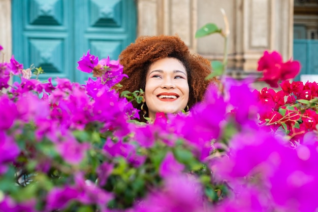 Portrait of a smiling redhaired woman among lilac and red flowers with green leaves confident and calm person