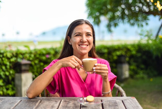 Portrait of smiling russian woman drinking hot capuccino and looking left