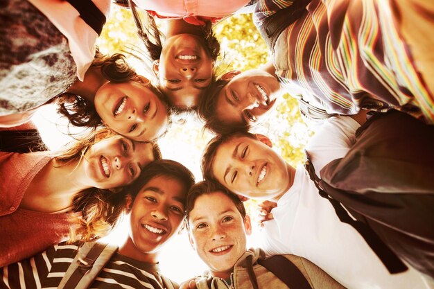 Portrait of smiling school kids forming a huddle in campus