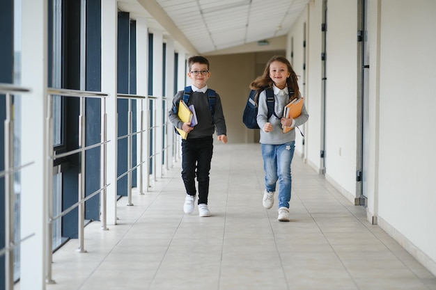 Портрет улыбающихся школьников в школьном коридоре с книгами