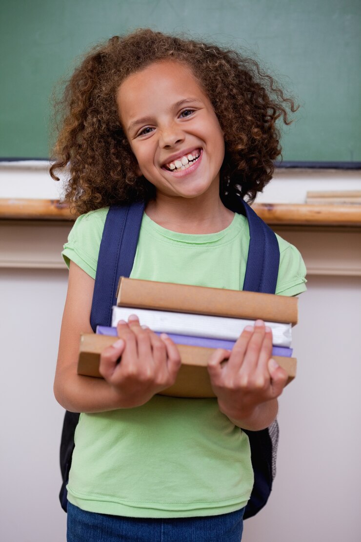 Photo portrait of a smiling schoolgirl holding her books