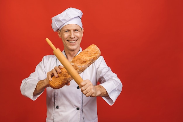 Portrait of smiling senior baker. Isolated over red background.