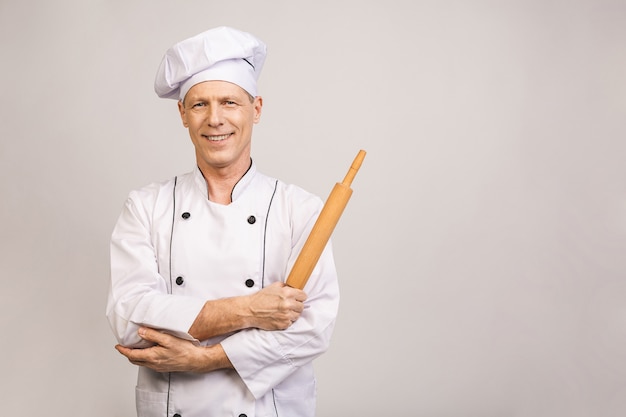 Portrait of smiling senior baker. Isolated over white wall.