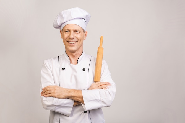 Portrait of smiling senior baker. Isolated over white wall.