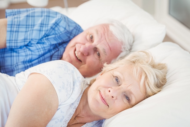 Portrait of smiling senior couple relaxing on bed