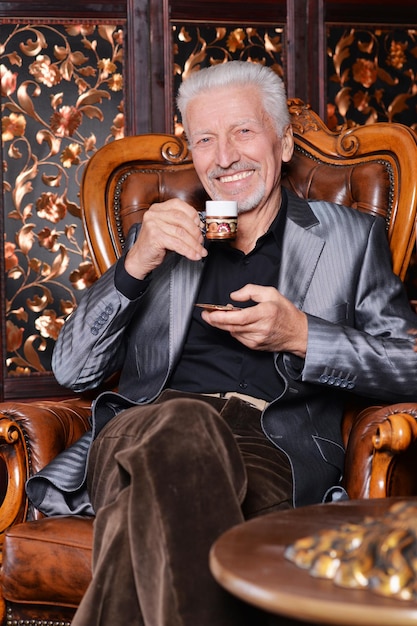 Portrait of smiling senior man drinking coffee at home