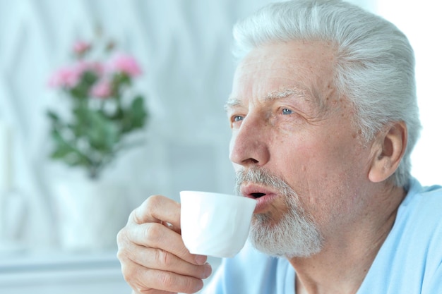 家でコーヒーを飲む笑顔の年配の男性の肖像画