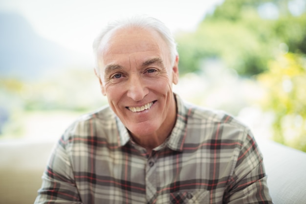 Portrait of smiling senior man sitting on sofa in living room