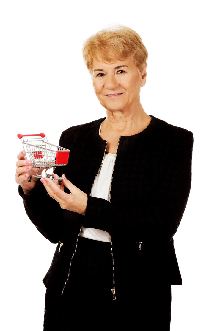 Photo portrait of smiling senior woman holding shopping cart against white background