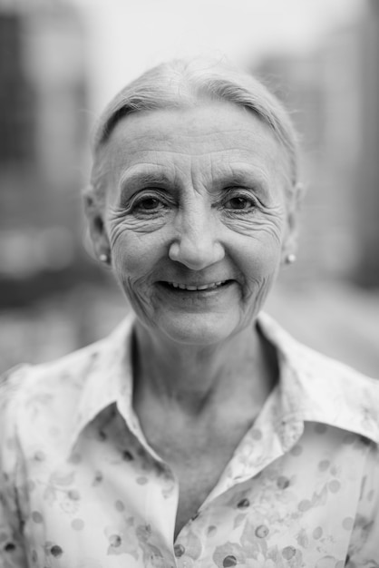 Портрет улыбающейся пожилой женщины на открытом воздухе