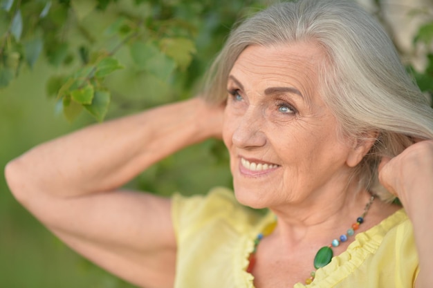 Portrait of smiling senior woman in park in summer