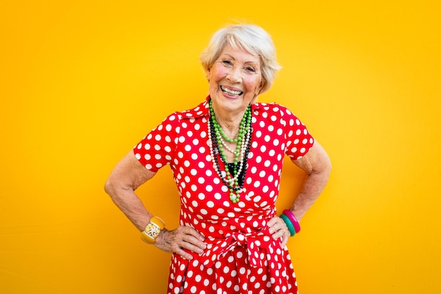 Foto ritratto di una donna anziana sorridente in piedi su uno sfondo giallo