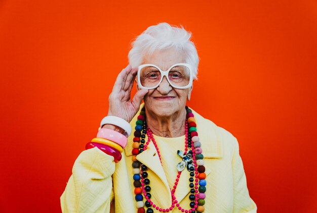 Portrait of smiling senior woman wearing eyeglasses against red background