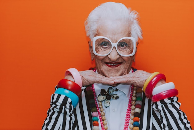 Photo portrait of smiling senior woman wearing eyeglasses against red background