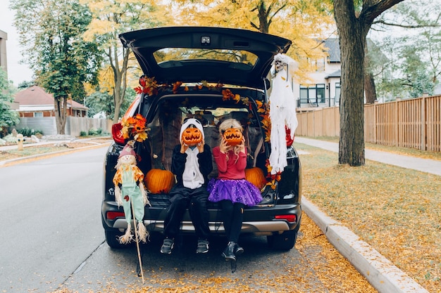 Photo portrait of smiling sibling sitting in car trunk outdoors