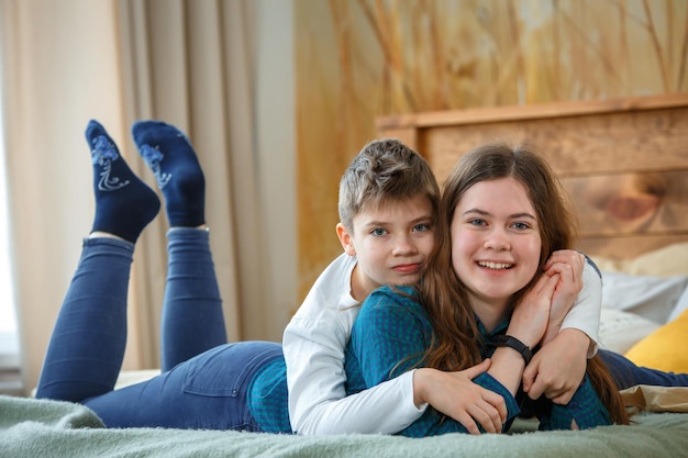 Portrait of smiling siblings lying on bed at home