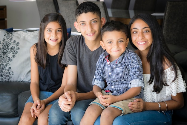 Photo portrait of smiling siblings sitting on sofa at home