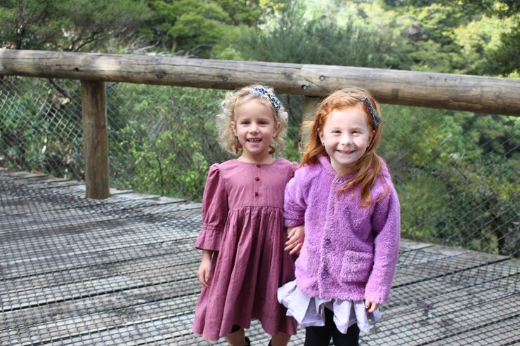 Photo portrait of smiling sisters standing on footbridge